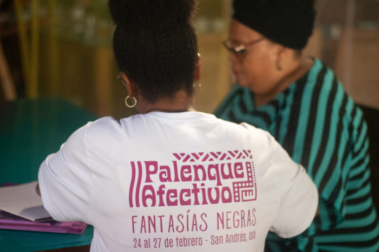 Mujer afro con camiseta de Palenque Afectivo en evento Fantasías Negras, San Andrés Isla, junto a otra participante en conversación